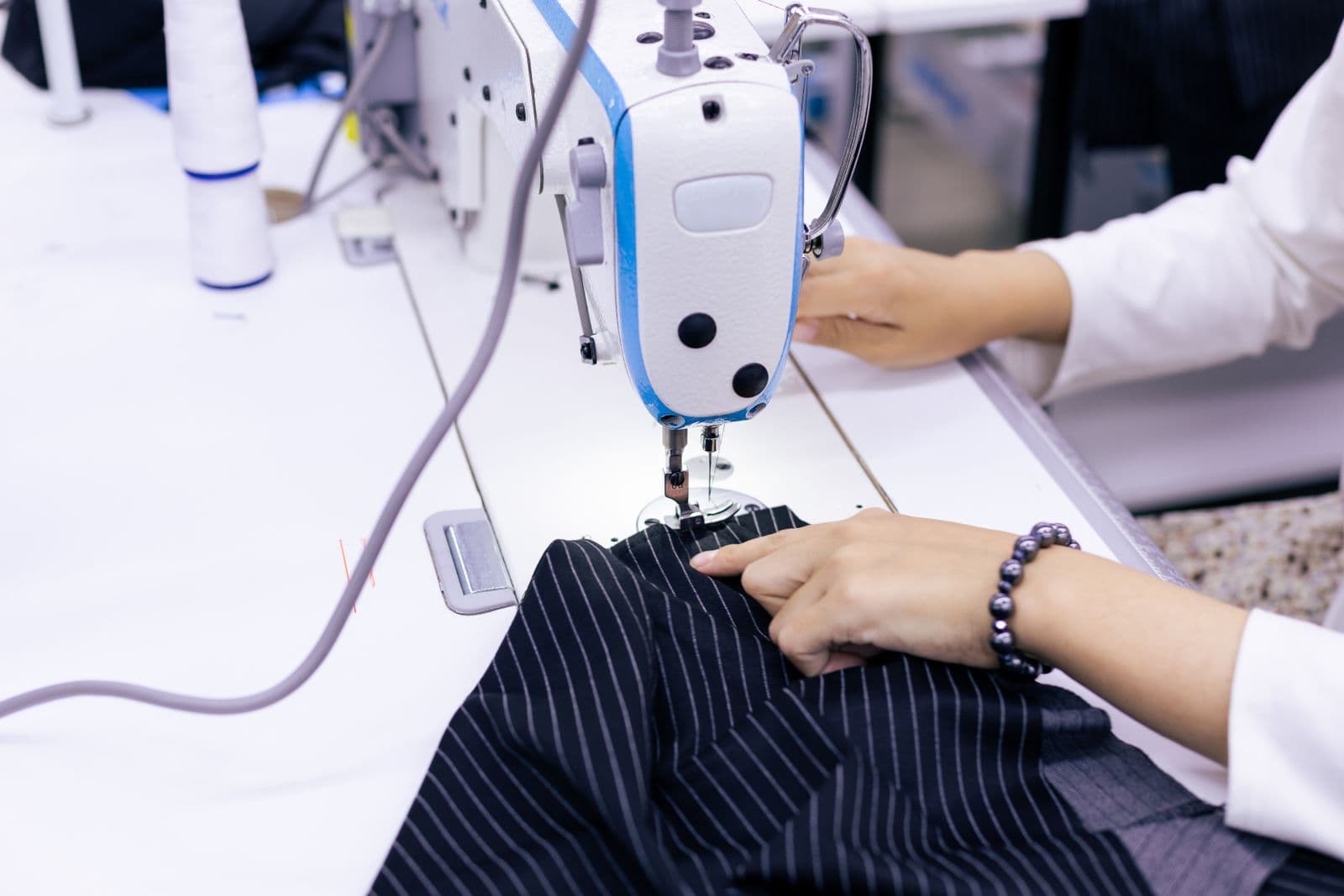 Garment worker stitching striped fabric at an industrial sewing machine